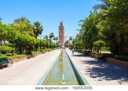 Marrakesh Morocco - May 12 2017: Tourists and locals are relaxing in the Koutoubia Gardens on a sunny day with the Koutoubia Mosque in the background.