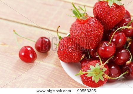 Fruit background cherry and strawberry on wooden table. View from above with copy space