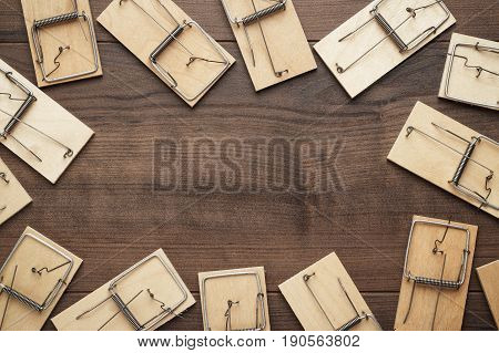 many mousetraps frame with copy space. mousetraps on the brown table. background with wooden mousetraps. lots of mousetraps background