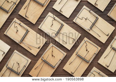 many mousetraps in order. mousetraps on the brown table. background with wooden mousetraps. lots of mousetraps background