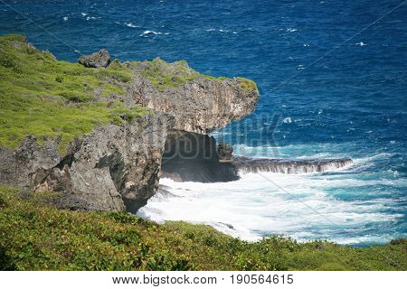 jutting rocks above the blue ocean 
Rock formation showing a jutting point just above a rock platform in the ocean