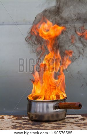 Vertical shot of saucepan on fire with huge firery flames shooting up