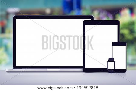 Responsive design mockup of laptop, tablet, smartphone and smartwatch on office desk.