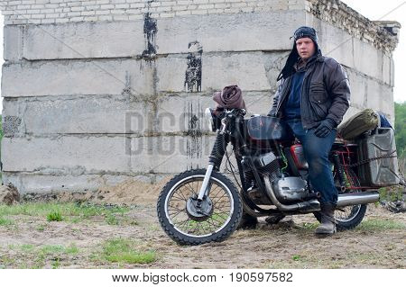 A post apocalyptic man on motorcycle near destroyed building