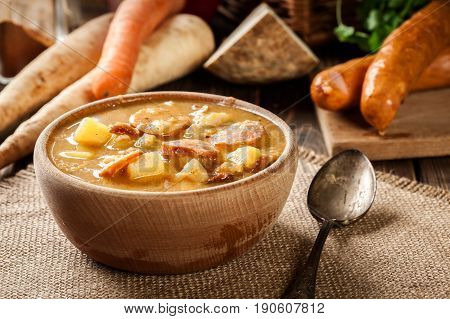 Wooden Bowl Of Split Pea Soup With Sausage And Potatoes