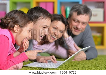 Big happy family lying on floor in front of laptop