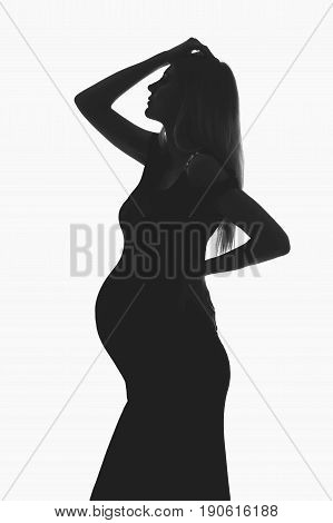 Beautiful pregnant young woman in long black dress. Studio portrait isolated on white background. Copy space. Monochrome