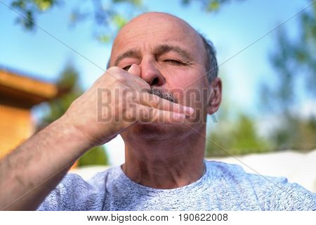 Handsome mature man with mustache breathing yoga pranayama on summer sunny day outside.