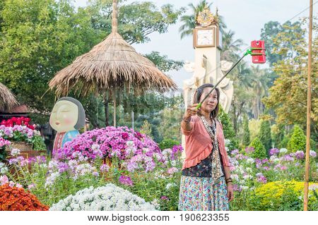 CHIANG MAI, THAILAND - FEBRUARY 6, 2016: Woman takes a selfie during Chiang Mai Flower Festival at Buak Hard Public Park in Chiang Mai. This year the world famous festival celebrated its 40th anniversary.