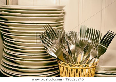 A stack of washed dishes and forks in the kitchen.
