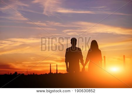 Young Couple Is Holding Hands On A Background Sunset Silhouette
