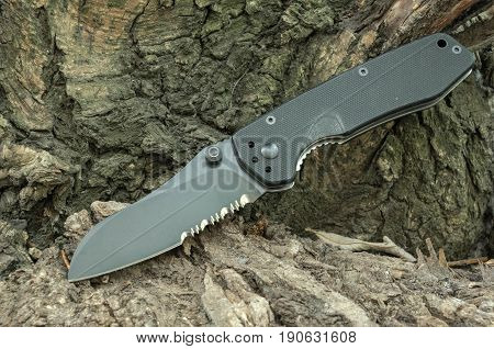 Black Knife On A Tree Bark. Pocket Knife. Tourist Knife.