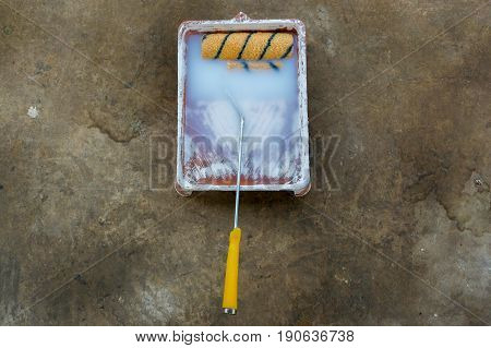 Used painting roller resting on tray container.