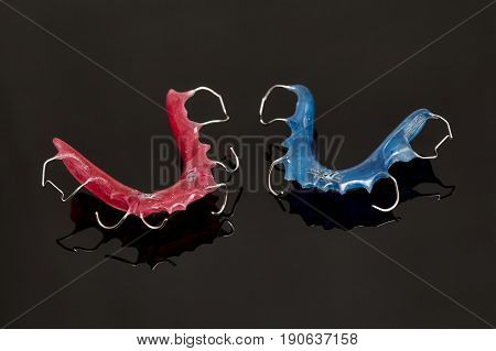 Colorful dental braces or retainers for teeth on black glass background closeup