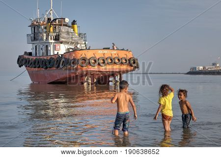 Bandar Abbas Hormozgan Province Iran - 16 april 2017: Iranian children play in the shallows near the boat which ran aground.