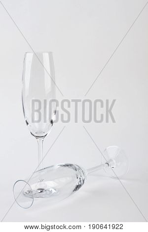 Two champagne glasses, one fell. Vertical image, clear wine glasses.