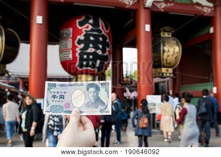Tokyo Japan - April 23 2017 : Touris hold 1000 japanese yen banknote with Kaminarimon gate at Asakusa shrine background