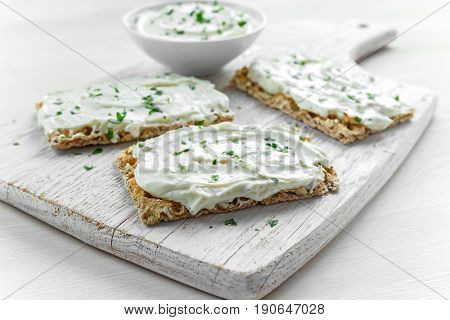 Homemade Crispbread toast with Cream Cheese and parsley on white wooden board background