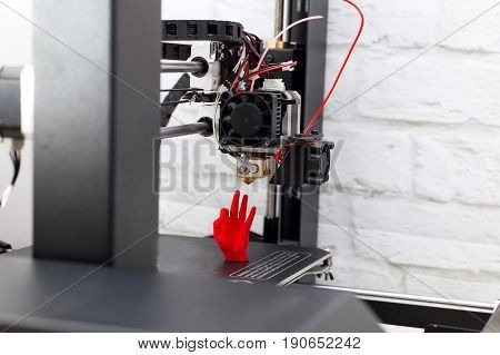 3d Printer prints a red plastic hand figurine