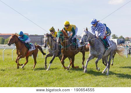 STOCKHOLM SWEDEN - JUNE 06 2017: Four jockeys side by side riding gallop arabian race horses at Nationaldags Galoppen at Gardet. June 6 2017 in Stockholm Sweden