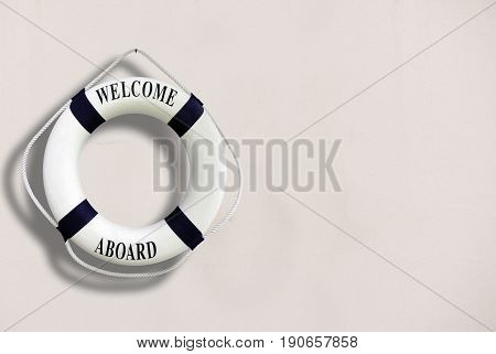 White Color Life Buoyancy With Welcome Aboard On It Hanging On White Concrete Wall.had Space On Righ