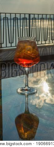 Waiter prepared the Aperol Sprits summer cocktail with Aperol prosecco ice cubes and orange in wine glass ready to drink on sunny terrace with sea view