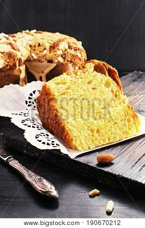 Slice of Colomba - italian easter dove cake on old rustic black wooden board. Selective focus free text space.