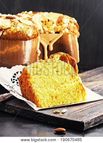 Slice of Colomba - italian easter dove cake on old rustic black wooden board. Selective focus free text space.