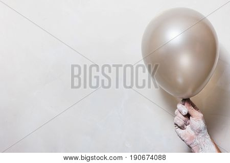 Dirty hand in plaster hold nacreous balloon on white background. Creative art backdrop with free space for idea or text.