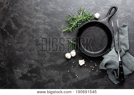 Empty cast iron frying pan on dark grey culinary background view from above