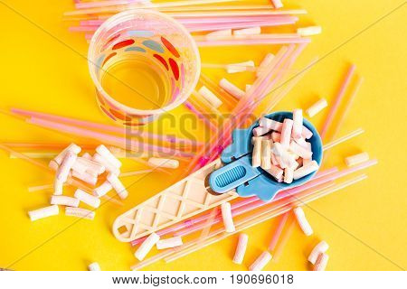 Multicolored Pastel background or colorful texture with top view. Pastel tasty fluffy sweet mini marshmallows. Minimal summer holiday style. Blue ice-cream Spoon and plastic cocktail ducts