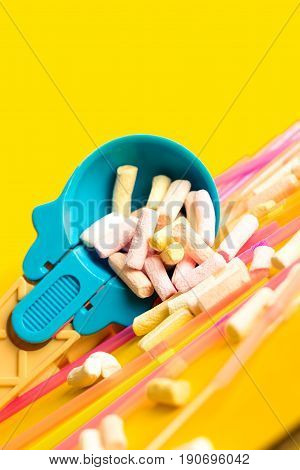 Multicolored Pastel background or colorful texture with top view. Pastel tasty fluffy sweet mini marshmallows. Minimal summer holiday style. Blue ice-cream Spoon and plastic cocktail ducts
