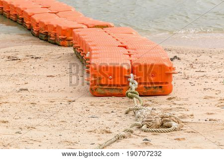 Close up end of orange sea buoys tied on sea beach marine equipment for marking safety zone.