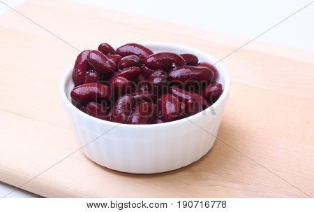 Heap of canned red kidney beans in the sauce in white bowl. vegetarian food. Phaseolus vulgaris
