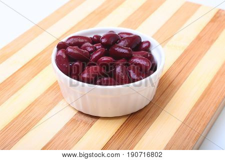 Heap of canned red kidney beans in the sauce in white bowl. vegetarian food. Phaseolus vulgaris