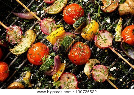 Grilled vegan skewers with cherry tomatoes, radishes, peppers and onions with fresh dill on a grill pan, top view
