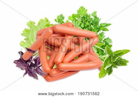 Pile of the uncooked frankfurters and twigs of purple basil green basil parsley and leaves of the lettuce on a light background