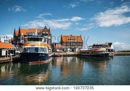 Volendam Netherlands - 26 April 2017: Harbor of Volendam with colorful tourist boats and promenade at sunny day Netherlands. Volendam is a popular tourist destination in North Holland