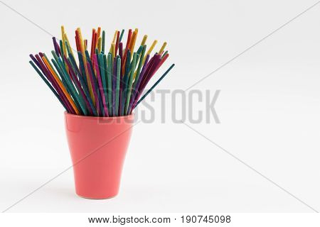 Colorful incense in mug on white background.