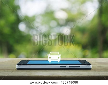 Car flat icon on modern smart phone screen on wooden table over blur green tree in park Business transportation service concept