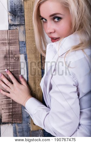 sexy girl in a man's shirt with big boobs on a wooden wall background.