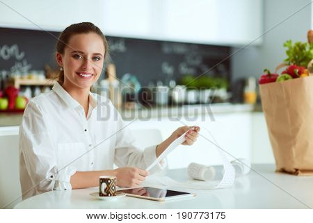 Young woman planning expenses and paying bills on her kitchen