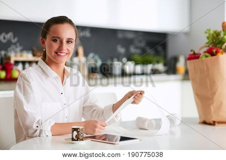 Young woman planning expenses and paying bills on her kitchen