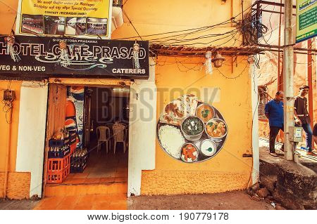PANJIM, INDIA - FEB 25, 2017: People going to small cafe with traditional indian food on February 25, 2017. Near 5 million tourists visit Goa annually