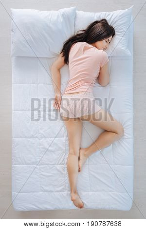 Time to relax. Attractive nice brunette woman lying in the bed and resting while having pleasant dreams