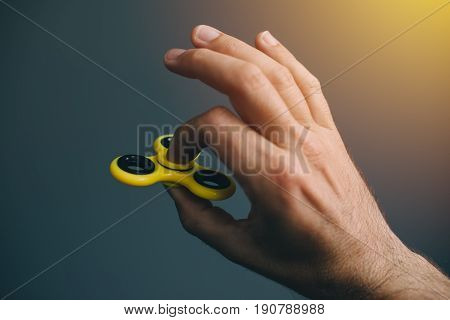 Yellow fidget spinner in male hand selective focus