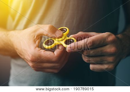 Yellow fidget spinner in male hand selective focus
