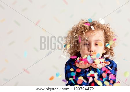 Young sweet boy making a mess with confetti