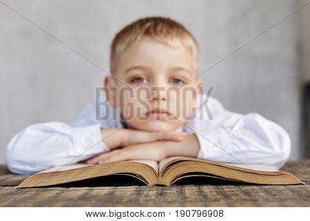 Long study hours. Tired exhausted handsome kid lying on a book while not enjoying the process of studying