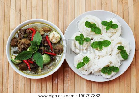 Thai-rice-flour noodles (kanom Jeen) arranged with green curry on brown wood floor